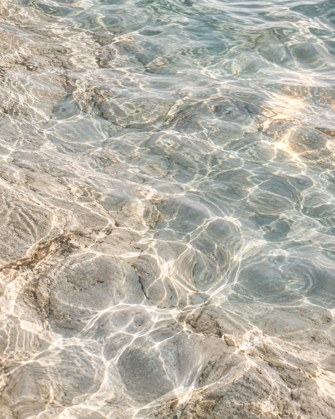 Agua clara sobre piedra con reflejos de luz.